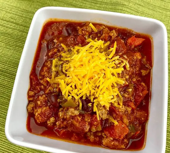 one pot chili recipe with shredded cheese in white bowl